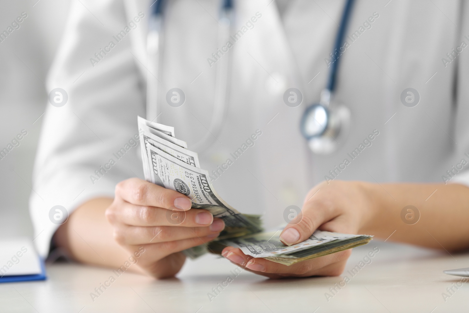 Photo of Doctor with bribe at desk in clinic, closeup. Corrupted medicine