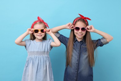 Cute little sisters on light blue background