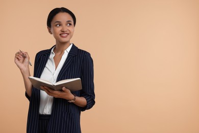 Photo of Beautiful secretary with notebook and pen on beige background, space for text