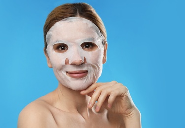 Photo of Beautiful woman with cotton mask sheet on face against color background