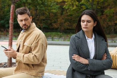Photo of Upset arguing couple sitting on bench in park. Relationship problems
