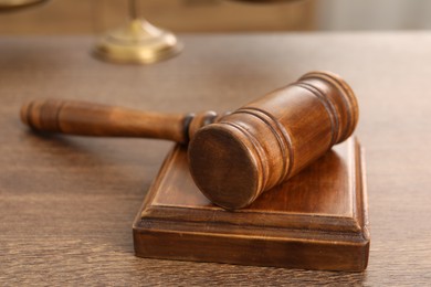 Photo of Wooden gavel and sound block on table indoors, closeup