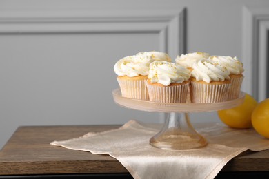 Photo of Delicious lemon cupcakes with white cream on wooden table, space for text