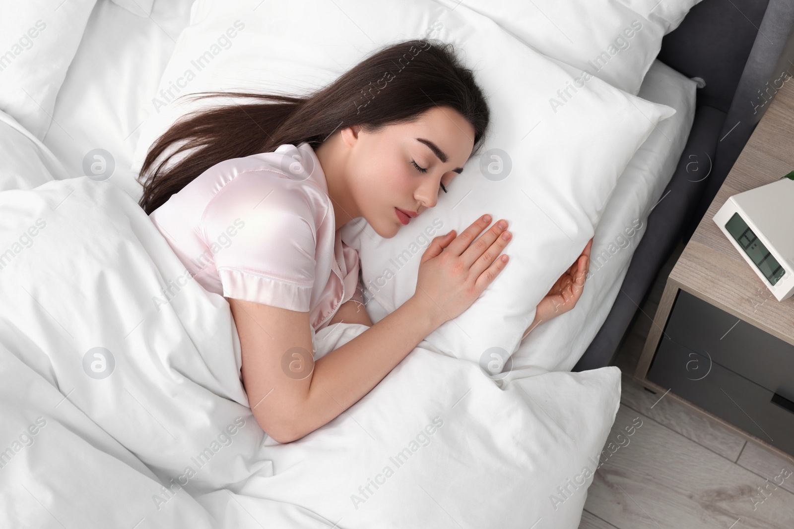 Photo of Beautiful young woman sleeping in soft bed at home, top view