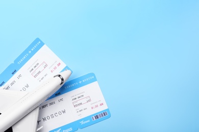 Photo of Toy airplane and tickets on light blue background, flat lay with space for text. Travel agency concept