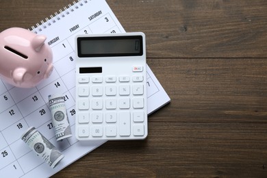Photo of Flat lay composition with piggy bank and calculator on wooden table, space for text. Paying bills concept