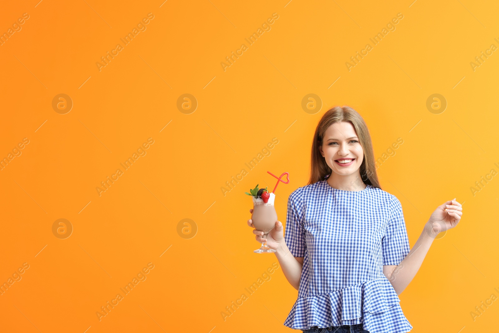 Photo of Young woman with glass of delicious milk shake on color background