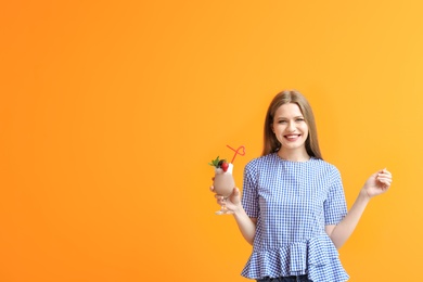 Young woman with glass of delicious milk shake on color background