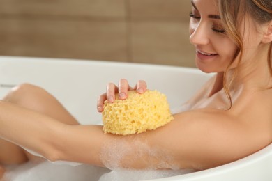 Beautiful woman with sponge taking bubble bath