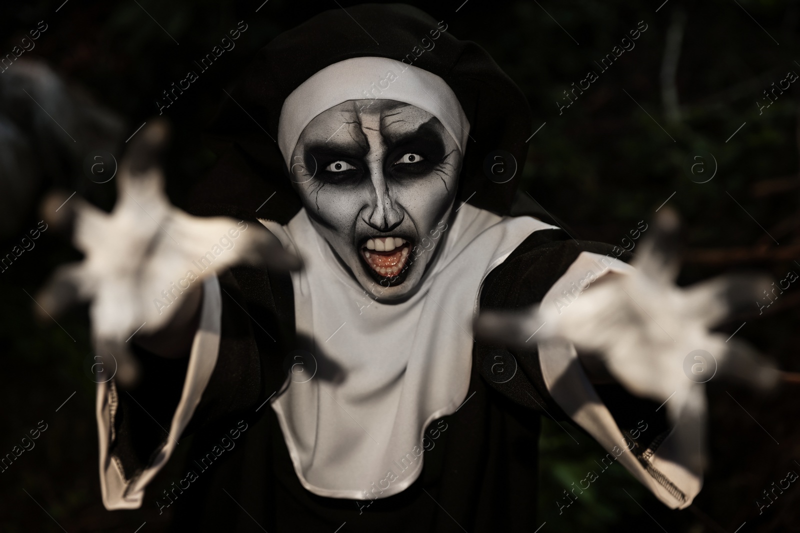 Photo of Scary devilish nun frightening outdoors. Halloween party look