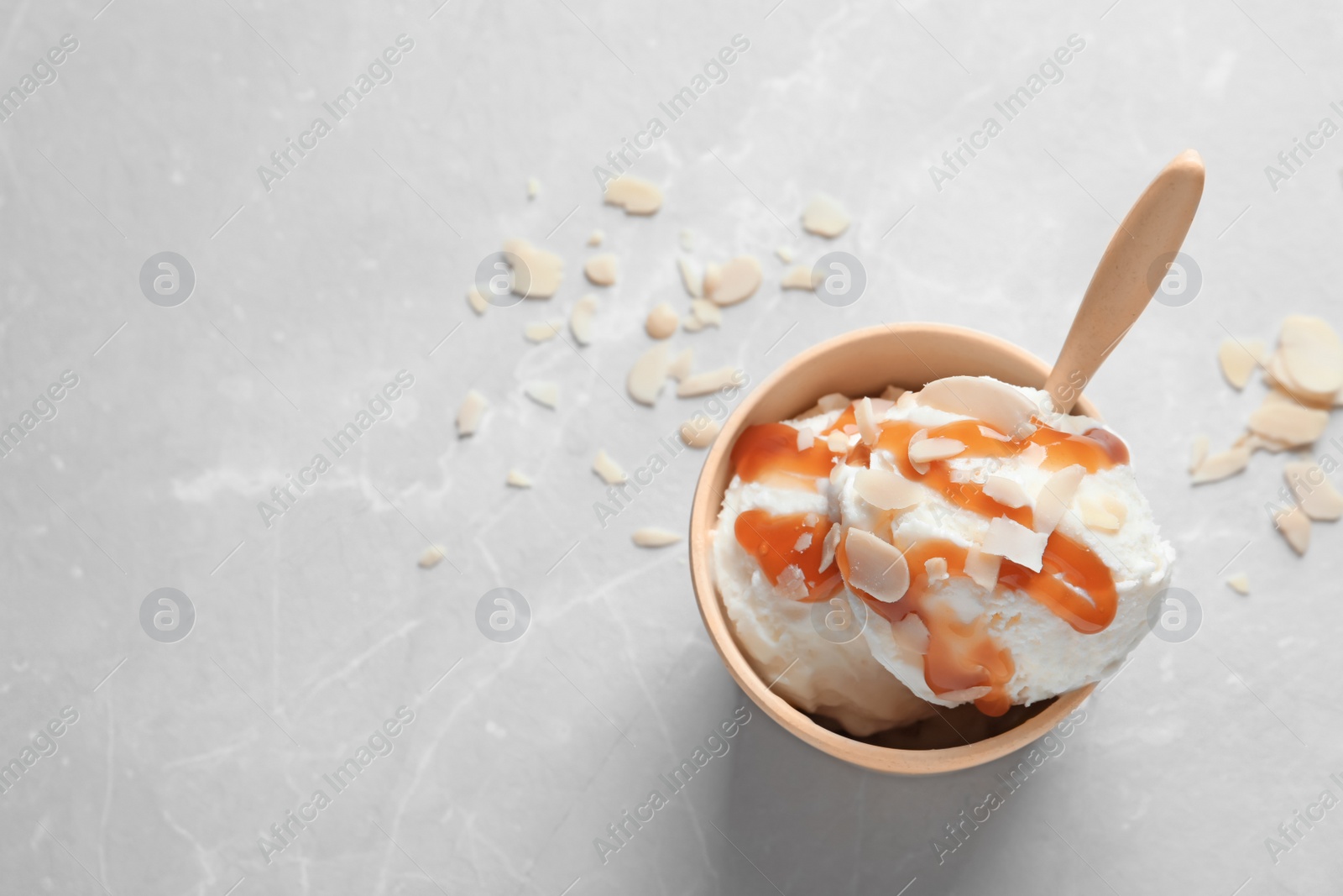 Photo of Bowl with caramel ice cream on light background