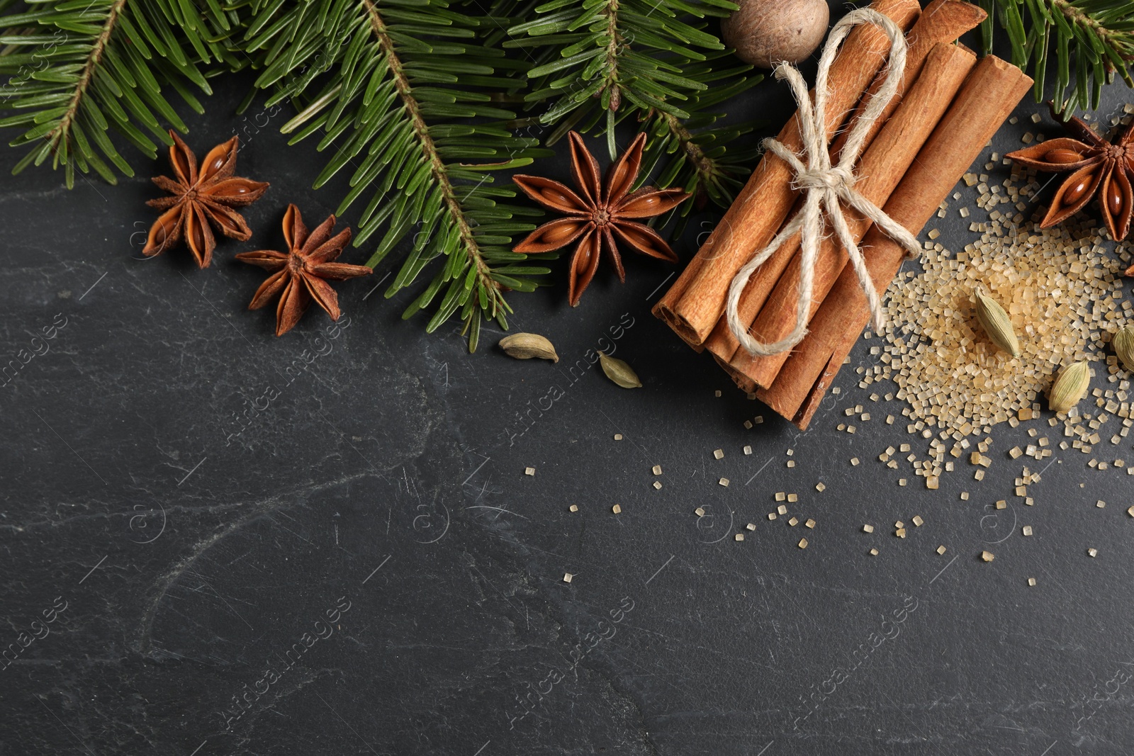 Photo of Different spices, nut and fir branches on gray table, flat lay. Space for text