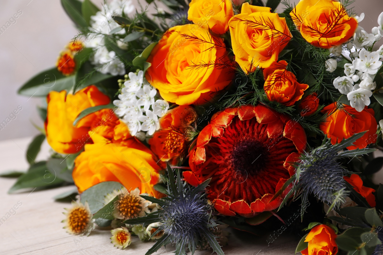 Image of Beautiful bouquet with roses on white wooden table, closeup