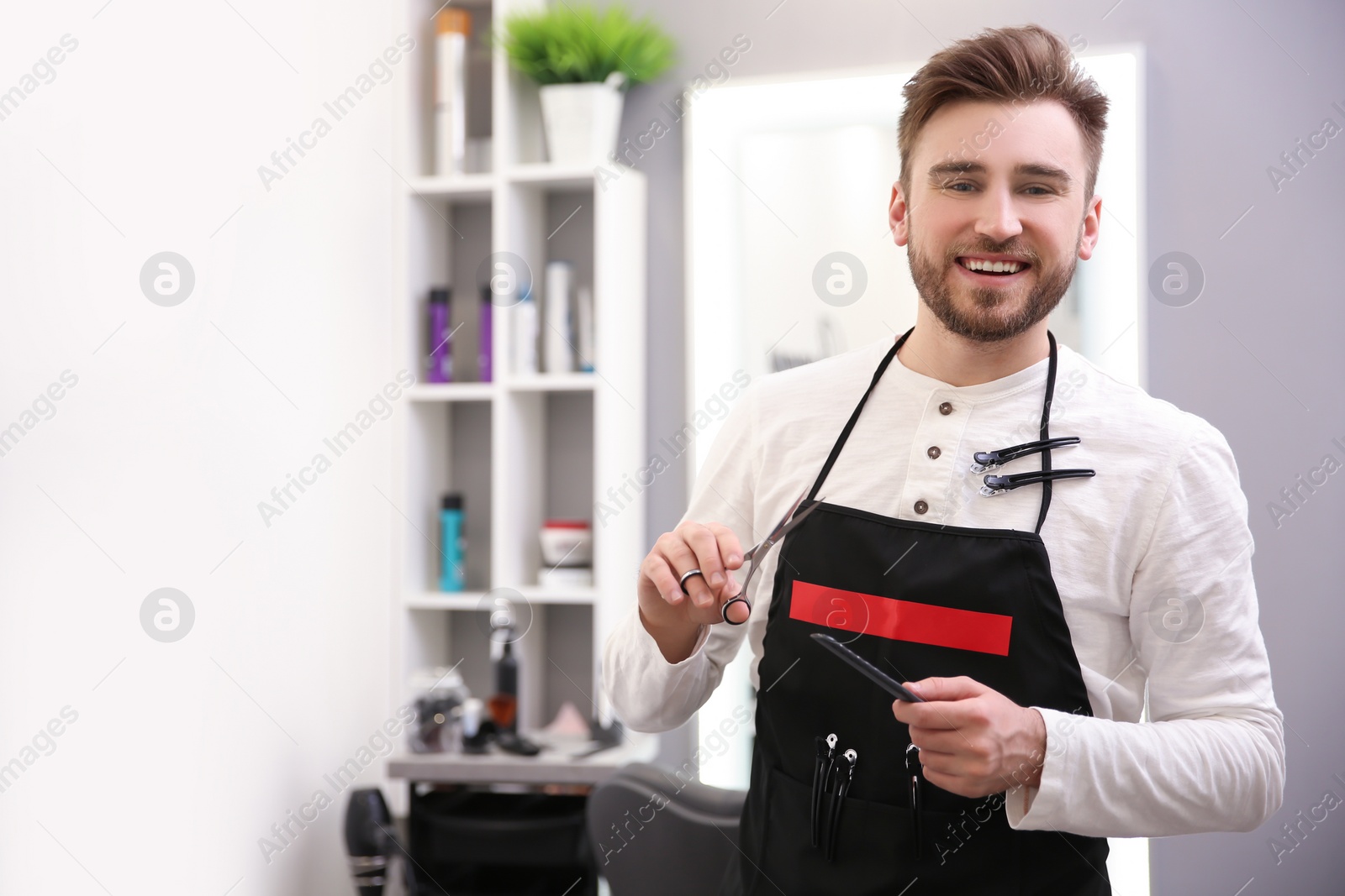 Photo of Professional male hairdresser with comb and scissors in salon