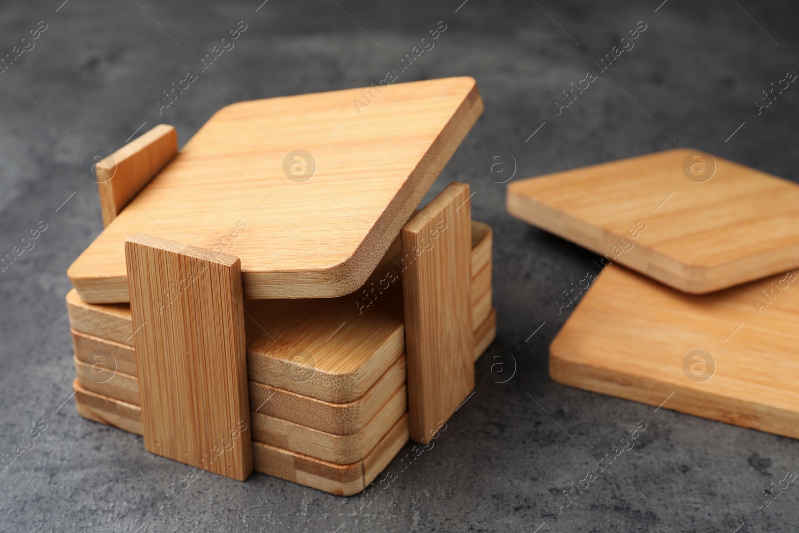 Photo of Stylish wooden cup coasters and holder on grey table