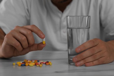 Photo of Man with antidepressant pills and glass of water at table, closeup