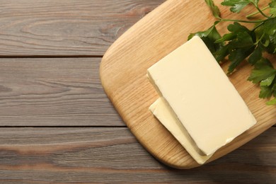 Photo of Tasty butter and parsley on wooden table, top view. Space for text