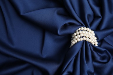 Beautiful pearls with dark blue silk as background, space for text