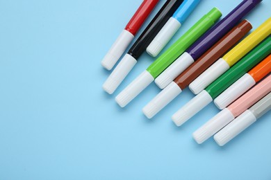 Many different colorful markers on light blue background, flat lay. Space for text