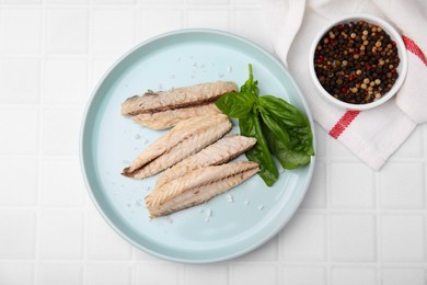 Photo of Canned mackerel fillets served on white tiled table, flat lay