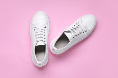 Photo of Pair of stylish white sneakers on pink background, top view