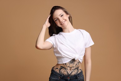 Portrait of smiling tattooed woman on beige background