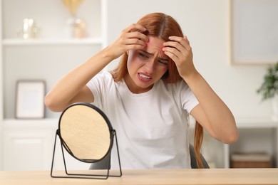 Photo of Suffering from allergy. Young woman with mirror checking her face at home