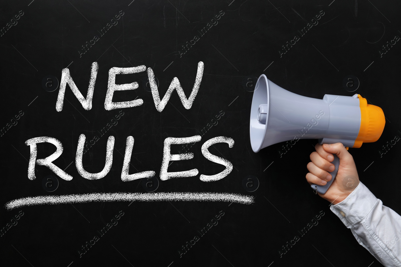 Image of Man holding megaphone and text NEW RULES on chalkboard, closeup