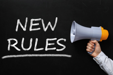 Image of Man holding megaphone and text NEW RULES on chalkboard, closeup