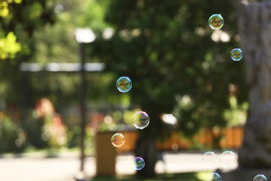 Photo of Beautiful translucent soap bubbles outdoors on sunny day