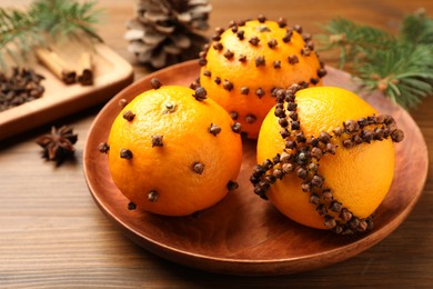 Pomander balls made of tangerines with cloves on wooden table