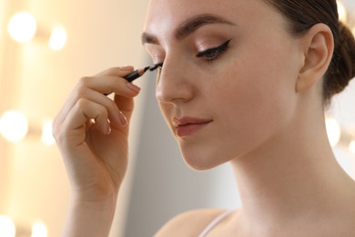 Makeup product. Woman applying black eyeliner indoors, closeup