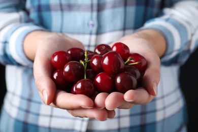 Photo of Woman with pile of ripe cherries, closeup