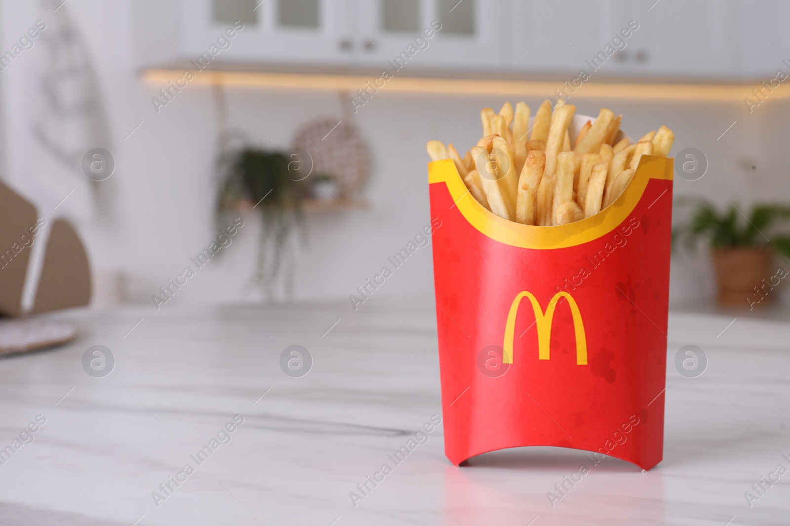 Photo of MYKOLAIV, UKRAINE - AUGUST 12, 2021: Big portion of McDonald's French fries on marble table in kitchen. Space for text