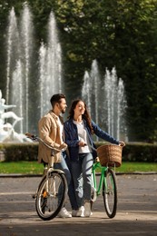 Beautiful couple with bicycles spending time together in park