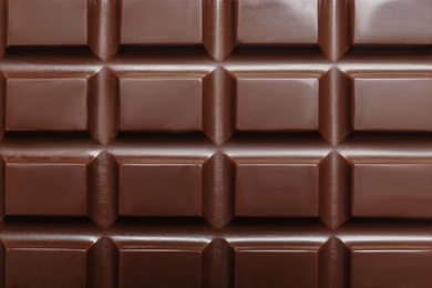 Photo of Tasty dark chocolate bar as background, top view