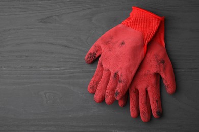 Photo of Pair of red gardening gloves on grey wooden table, top view. Space for text