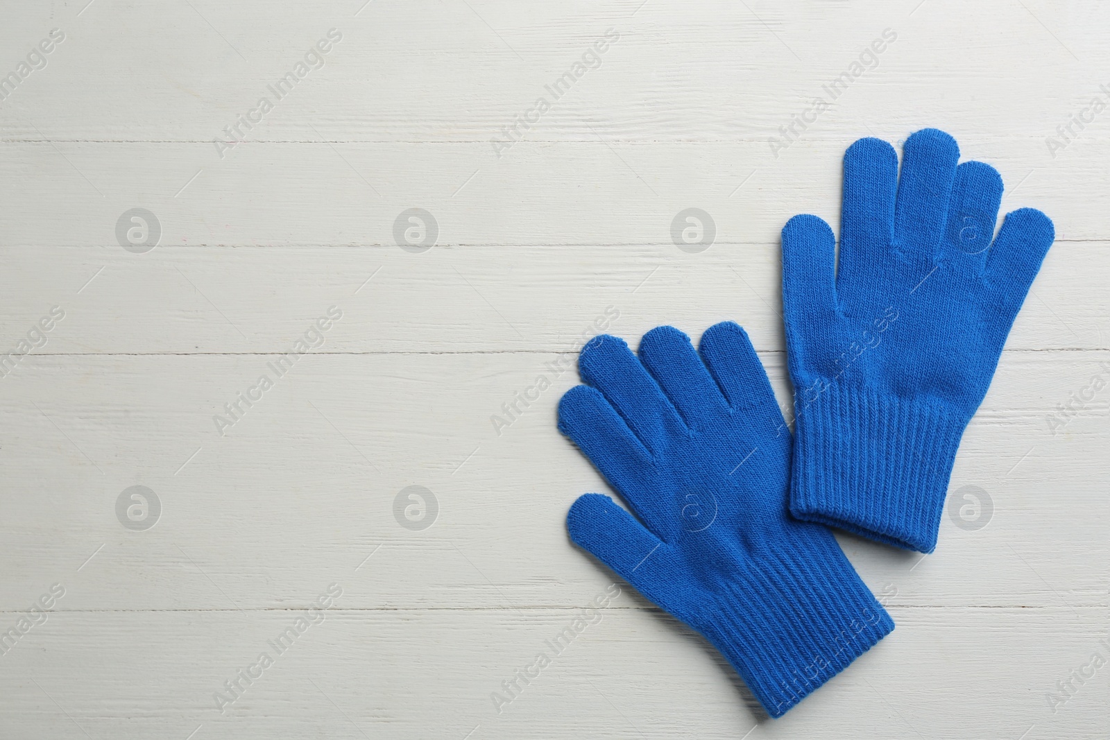 Photo of Pair of stylish woolen gloves on white wooden background, flat lay. Space for text