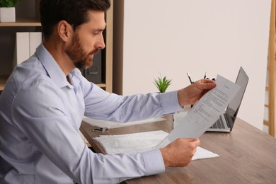 Businessman reading document at wooden table in office
