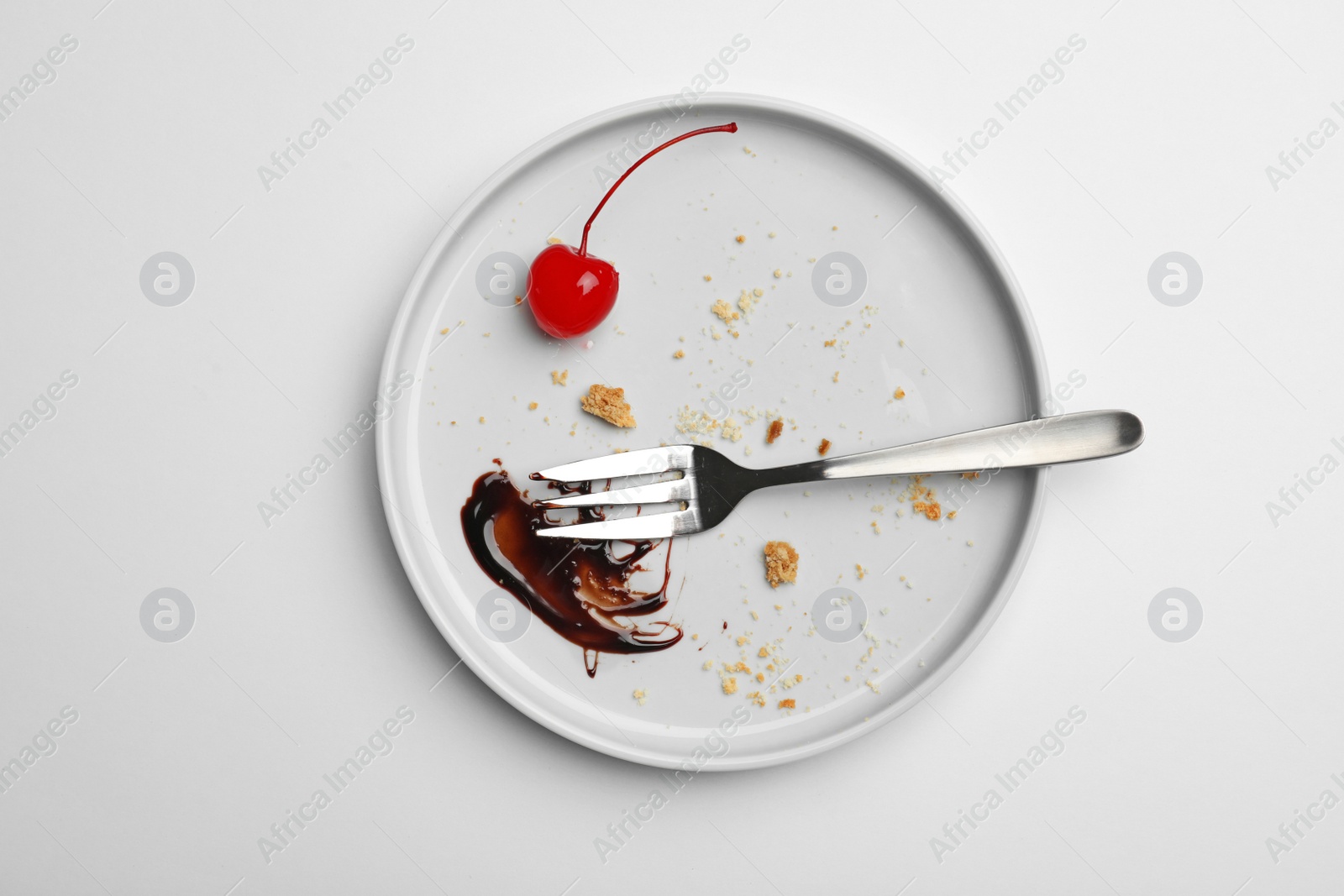 Photo of Dirty plate with food leftovers, fork and canned cherry on white background, top view