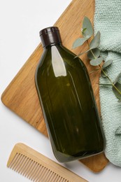 Photo of Bottle of shampoo, comb and green branch on white table, flat lay