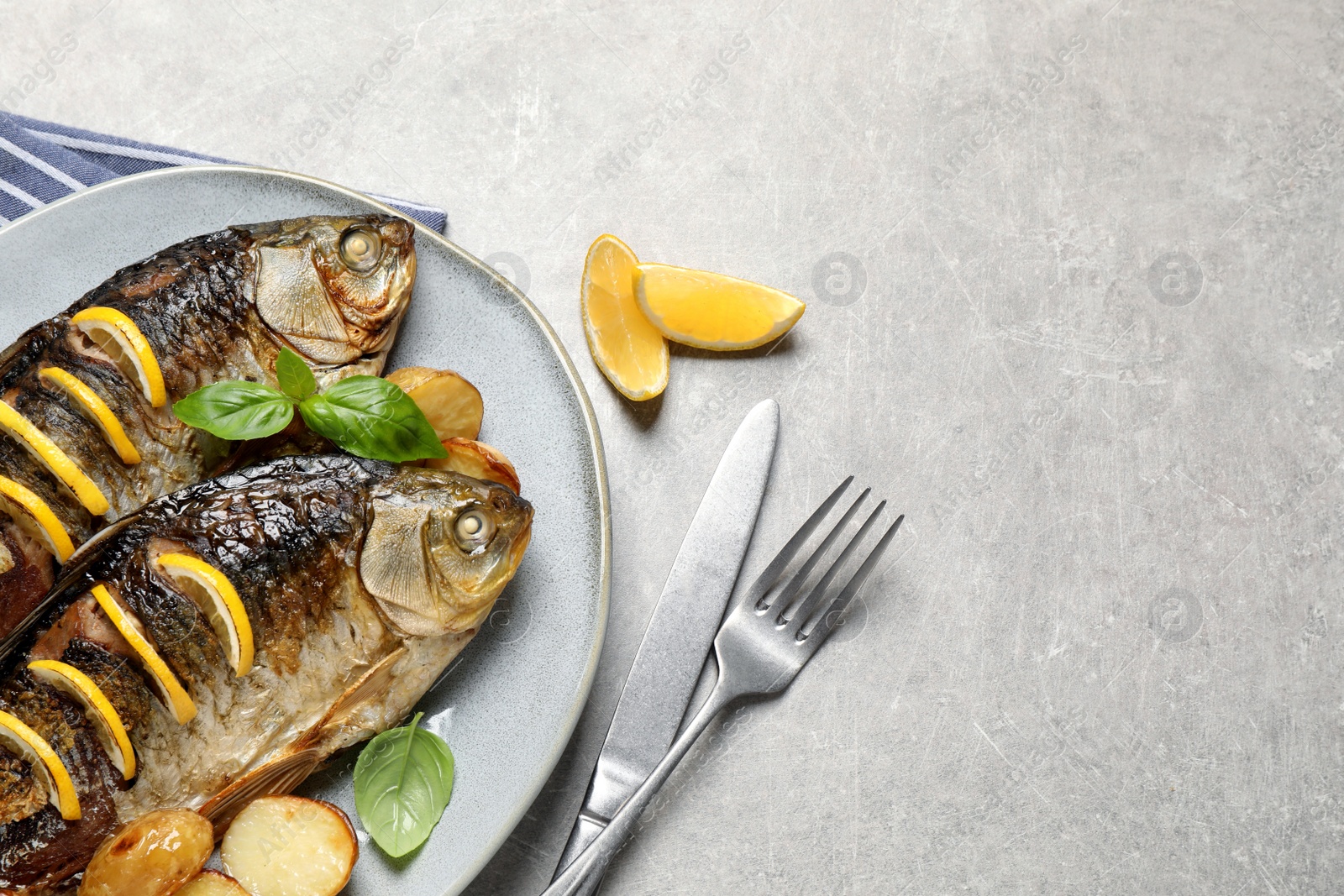 Photo of Tasty homemade roasted crucian carps served on light grey table, flat lay and space for text. River fish