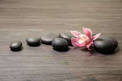 Photo of Spa stones with orchid flower on wooden background