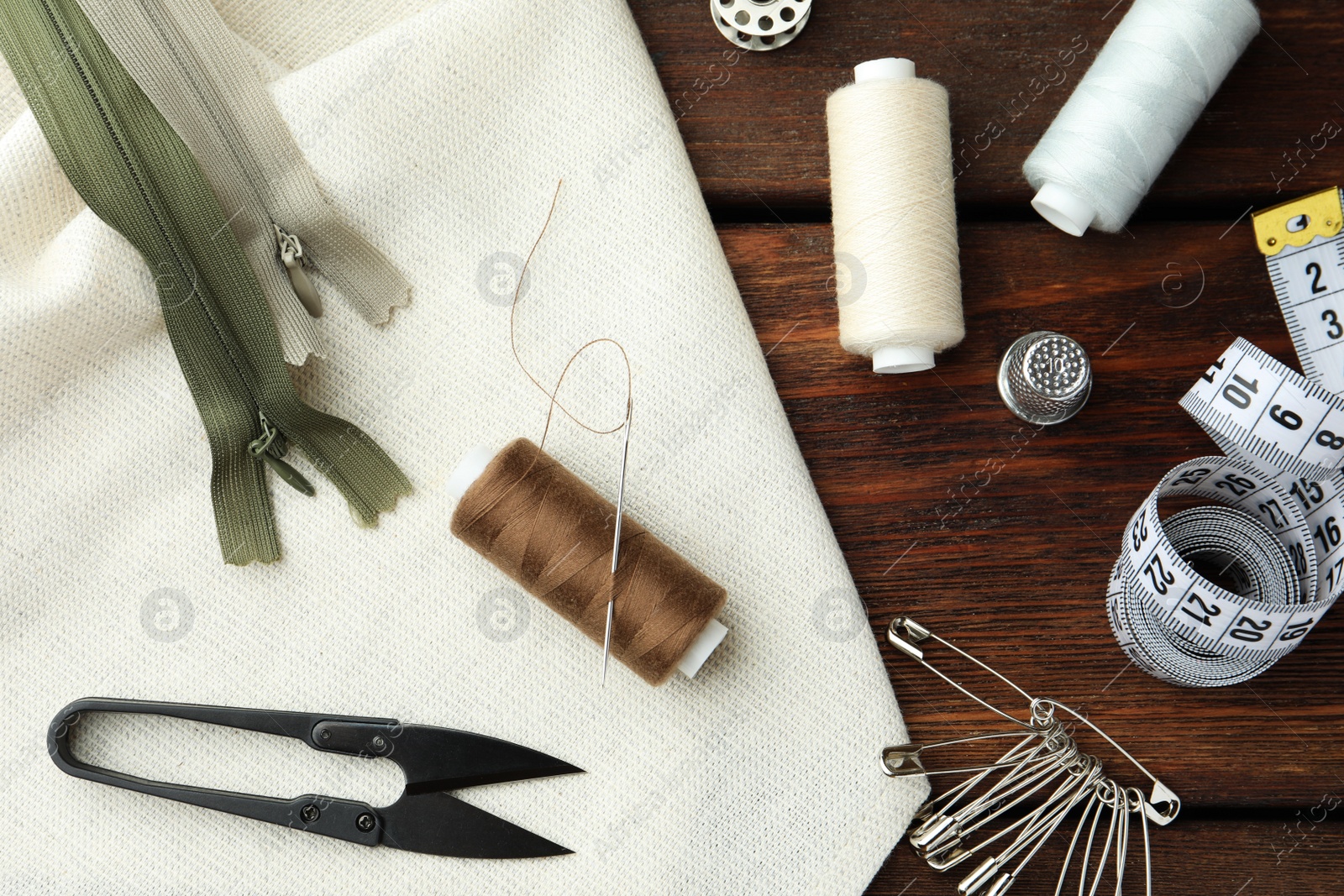 Photo of Threads and other sewing supplies on wooden table, flat lay
