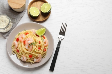 Plate with spaghetti and shrimps on light background, top view