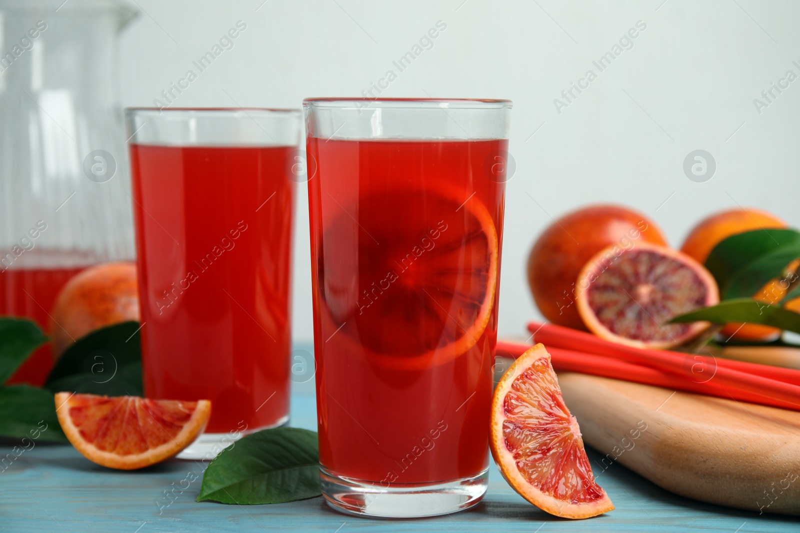 Photo of Tasty sicilian orange juice and fruits on light blue wooden table