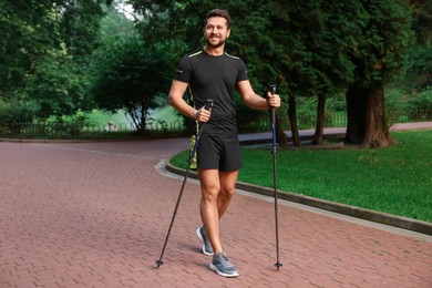 Photo of Man practicing Nordic walking with poles outdoors