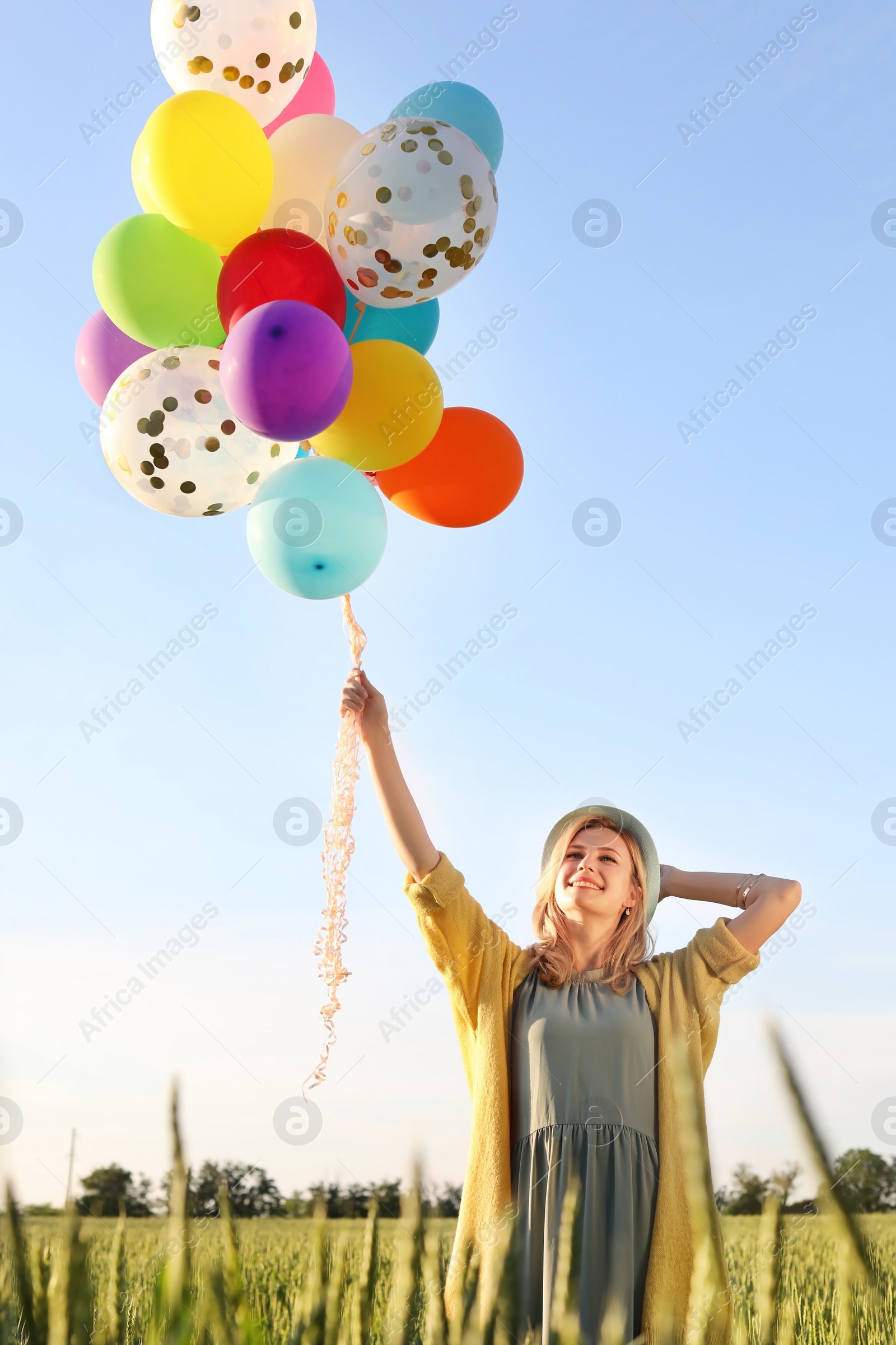 Photo of Young woman with colorful balloons outdoors on sunny day