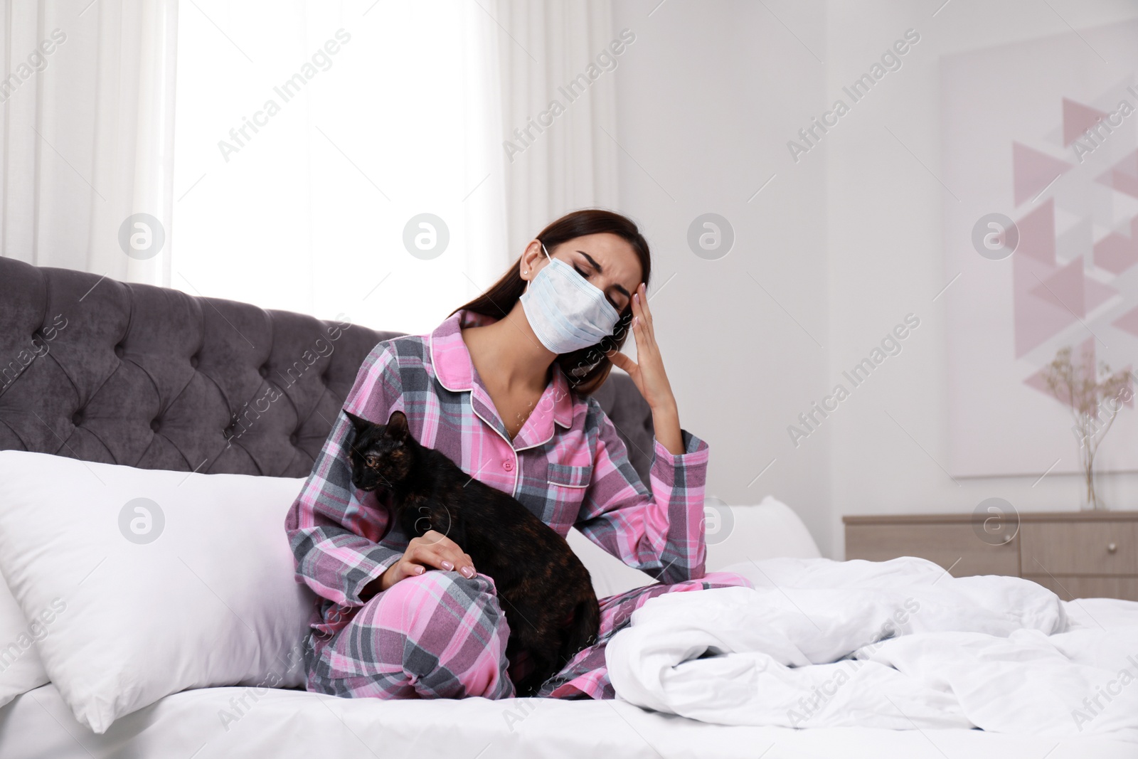 Photo of Young woman with cat suffering from allergy in bedroom