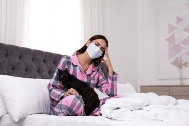 Photo of Young woman with cat suffering from allergy in bedroom